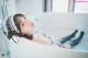 A woman laying in a bathtub wearing a maid outfit.