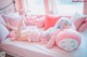 A woman laying on a bed with a pink stuffed animal.