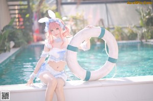 A woman in a bunny costume sitting next to a swimming pool.