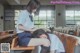 A woman sitting on a bench next to another woman in a classroom.