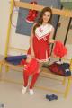 A young woman in a red and white cheerleading uniform posing for the camera.