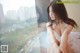A woman sitting on a window sill looking out a window.