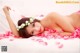 A naked woman laying on a bed covered in rose petals.