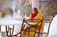 A woman sitting at a table in a yellow coat.