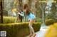 A woman in a blue dress and red high heels leaning against a tree.