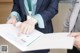 A woman in a business suit pointing at a document.