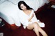 A woman in a white robe sitting on a bed.