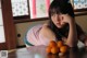 A woman sitting at a table with a bunch of oranges.