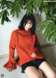A woman in a red sweater sitting on the floor.