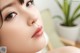 a close up of a woman's face with a plant in the background